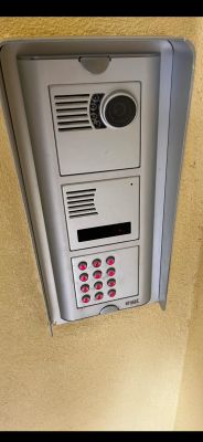 Widok domofonu Urmet Sceitel 1132 z kamerą i przyciskami, zamontowanego na ścianie.
