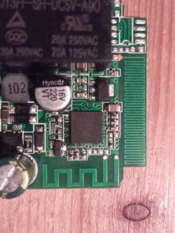 Close-up of electronic board with PCB antenna and relay Electronic module with relay, capacitors, and PCB antenna on wooden surface