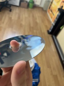 Osoba trzyma płytę CD z widoczną zaparowaną plamą na powierzchni.