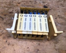 Module with six white relays and a PCB on a stained wooden workbench