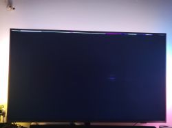 Telewizor z czarnym ekranem i widocznymi kolorowymi pikselami na górze.