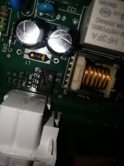 Zbliżenie na elektroniczną płytkę drukowaną z widocznym układem scalonym, dławikiem i kondensatorami.