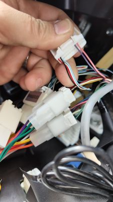 Zbliżenie na złącza kabli w samochodzie Toyota, z widocznymi różnokolorowymi przewodami i złączami.