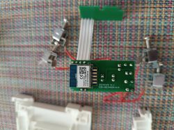 The image shows a disassembled electronic module purchased from Aliexpress, lying on a checkered fabric. Several screws and components are visible in the background.