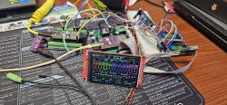 Electronics test setup with boards, breadboard, and a color display showing bar graphs