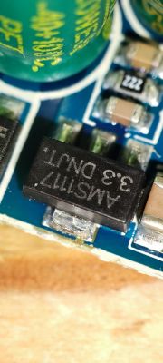 Close-up of electronic components on a printed circuit board, including a black chip labeled AMS1117 3.3 DNLT.