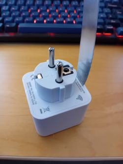 Smartplug on a Desk with Opening Tool A smartplug on a wooden desk with a tool for opening it.