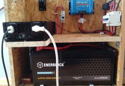 Widok instalacji fotowoltaicznej z akumulatorem Enerblock, falownikiem, kontrolerem ładowania i podłączonymi przewodami.