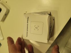 Human Presence Detector Box Box of a human presence detector on a table with a partially visible hand.