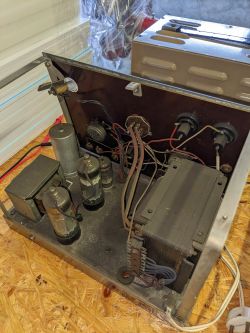 Wnętrze starego urządzenia elektronicznego z widocznymi lampami elektronowymi i transformatorami.