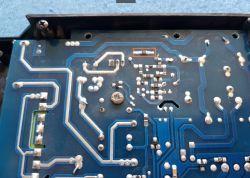 Spód płytki PCB z widocznymi ścieżkami i zaznaczonym elementem SMD w pomarańczowej ramce