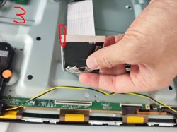 Osoba trzymająca taśmę łączącą wewnątrz telewizora Samsung UE50AU8002K.