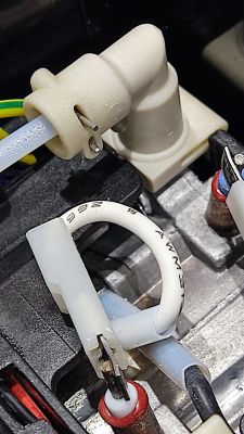 Zbliżenie na plastikowe kolanko i podłączone wężyki w ekspresie DeLonghi Dedica EC680.