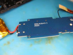 INO-A15-V1.1 circuit board with connected wires Blue circuit board labeled INO-A15-V1.1 AK23 with wires and a yellow battery