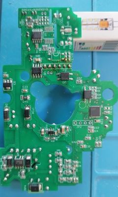 Printed circuit board (PCB) with electronic components, top view, an LED lamp packaging for size reference is visible.