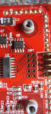 Zbliżenie na czerwoną płytkę drukowaną z układami scalonymi i komponentami elektronicznymi.