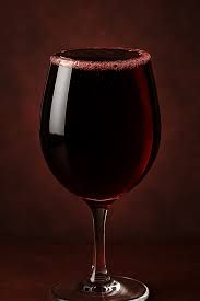 A glass of red wine on a dark background.