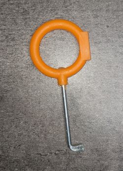 Orange hook with a metal tip on a gray surface.