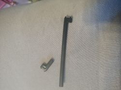 Two black plastic parts on grey fabric, likely components from a coffee machine