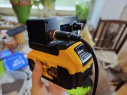 Przenośna lutownica na akumulator marki Dewalt trzymana w ręku, w domowym otoczeniu.