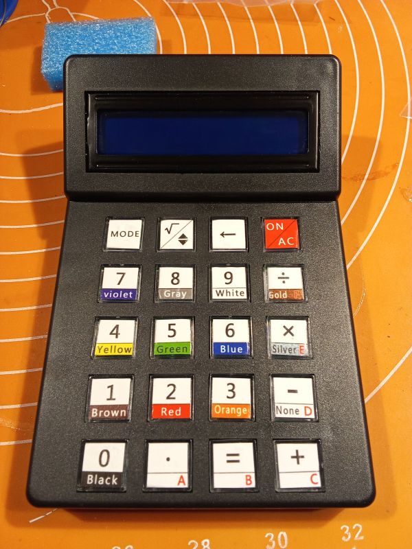 Elektroniczny kalkulator z wyświetlaczem i kolorowymi klawiszami na pomarańczowym tle.