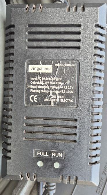 Czarna ładowarka Jingcheng model HBC-03 z opisanymi parametrami napięcia i prądu.