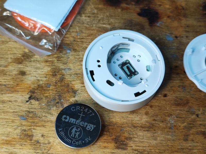 Wnętrze urządzenia Sonoff SNZB-01P z widoczną baterią CR2477