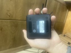 Osoba trzyma czarny router Apollo z widoczną naklejką identyfikacyjną na spodzie.