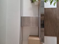 Okap kuchenny Samsung HC9247BX/XEO zamontowany między ścianą a szafką, z widoczną metalową osłoną kominową.