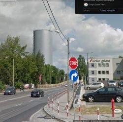 Duży cylindryczny zbiornik ciepła widziany z ulicy w Bielsku-Białej, obok kliniki i drogi z samochodami.