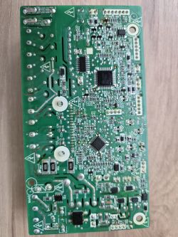 Zdjęcie płytki drukowanej z elementami elektronicznymi, leżącej na drewnianej powierzchni.