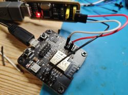 ESP32 development board with wired connections and a USB programmer on a workbench