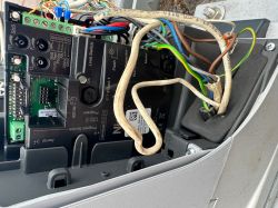 Zbliżenie na wnętrze automatyki bramy z przewodami i panelem sterującym.
