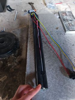 Wyjęta bateria hulajnogi elektrycznej ze zdjętą osłoną i widocznymi kolorowymi przewodami na stole roboczym.