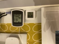 Dwa termometry elektroniczne pokazujące zbliżone temperatury na półce