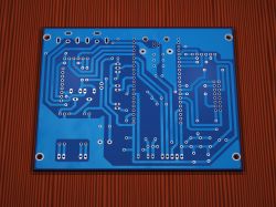Blue PCB with visible traces and mounting holes on a red textured background