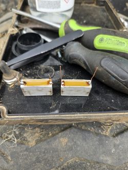 Dwa rezystory ceramiczne umieszczone na tacy z narzędziami w tle.