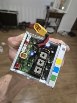 Sterownik elektroniczny trzymany w ręku, widoczna płytka z różnymi komponentami.