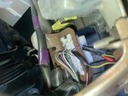Zbliżenie na wiązkę przewodów z kolorowymi kablami i białą kostką elektryczną.