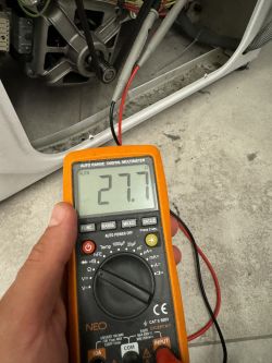 Cyfrowy multimetr pokazujący odczyt 27,7 Ω podczas pomiaru grzałki.