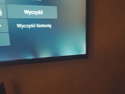 Zbliżenie dolnego rogu ekranu TV z jasnymi plamami i menu „Wyczyść”, „Wyczyść historię”
