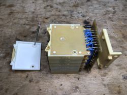 Disassembled relay module with PCB and blue wires on a wooden workbench