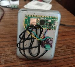 Raspberry Pi Pico 2W z przymocowanymi przewodami i wzmacniaczem na obudowie głośnika.