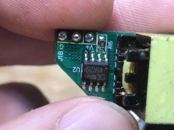 Close-up of a PCB with IC labeled U2 and a transformer, held between fingers