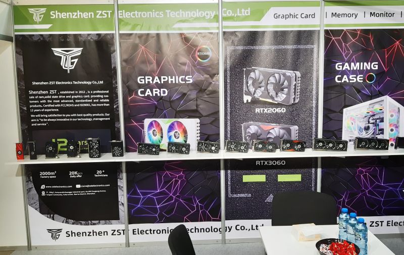 Stoisko firmy Shenzhen ZST na targach elektroniki, z kartami graficznymi i obudowami komputerowymi na ekspozycji.