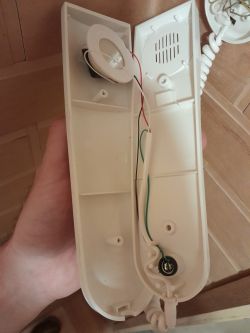 Rozłożony unifon interkomowy z widocznymi przewodami wewnętrznymi.
