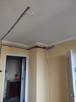 Widok na ścianę z odkrytymi przewodami elektrycznymi i rowkami do wypełnienia.