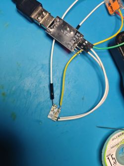 USB TTL Adapter with Connected Circuit Board USB TTL adapter connected to a circuit board on a blue background.
