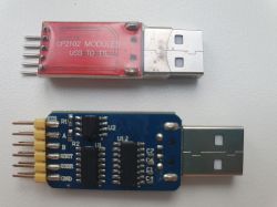 Two USB-TTL converter modules, one red and one blue, on a white background.