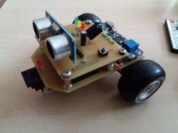 Mały robot na kółkach z zamontowaną płytką elektroniczną i czujnikami.